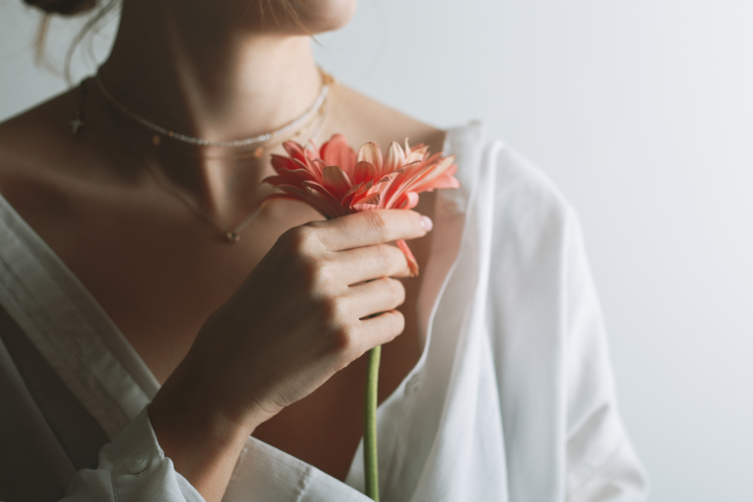 Person holding a red flower against a neutral background